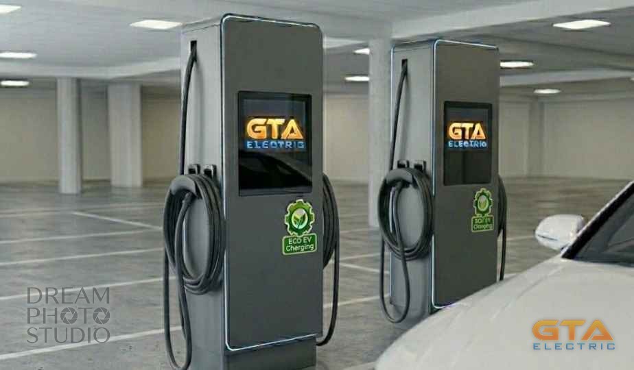Two GTA Electric commercial EV charging stations with branded touchscreens and ECO EV Charging badges in a clean underground parking garage, a white car charging alongside